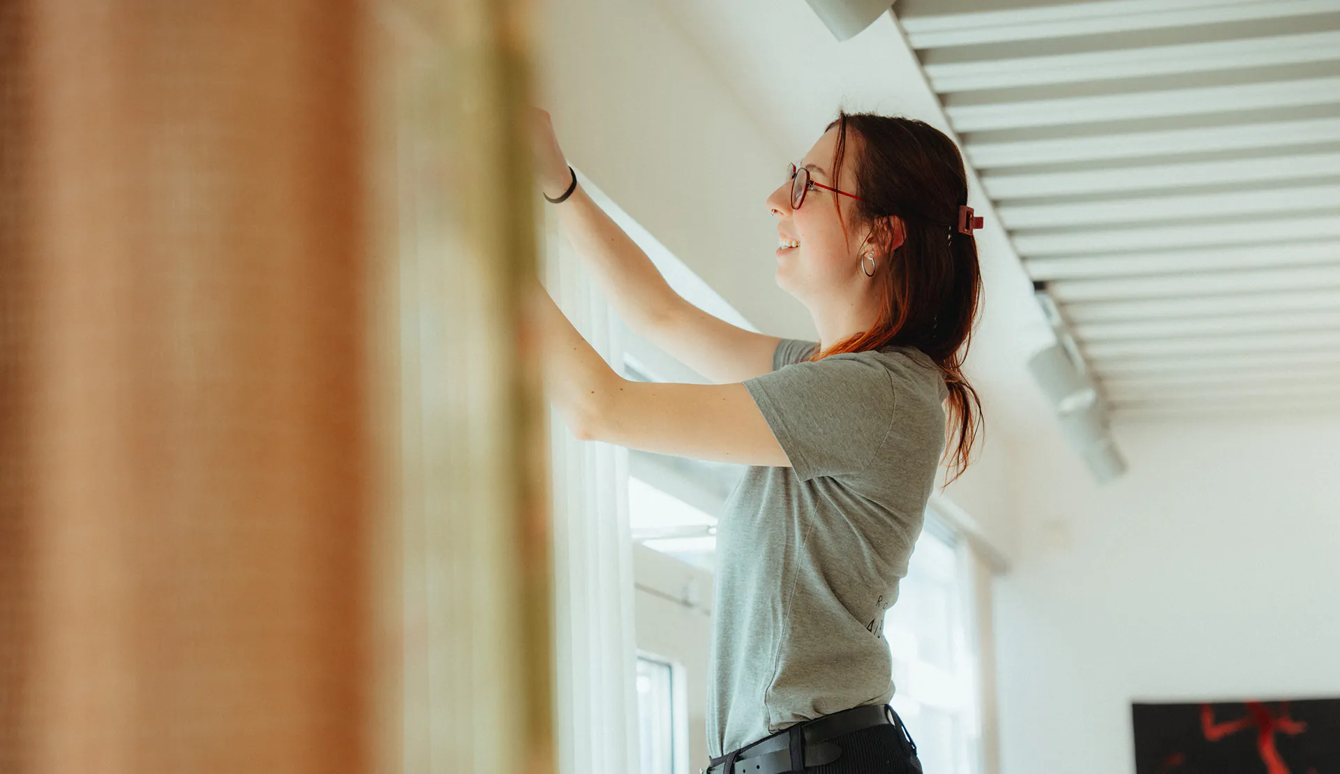 Mitarbeiterin von Albersmeyer richtet einen Vorhang am Fenster