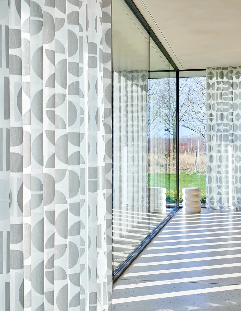 Transparente Gardinen mit grafischem Muster an einer bodentiefen Glasfront