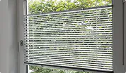 Jalousie am Fenster, dahinter Bäume