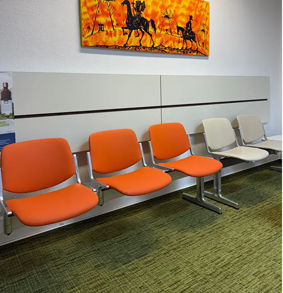 Wartebereich der Augenarztpraxis in Dillingen mit orangefarbenen Polsterstühlen