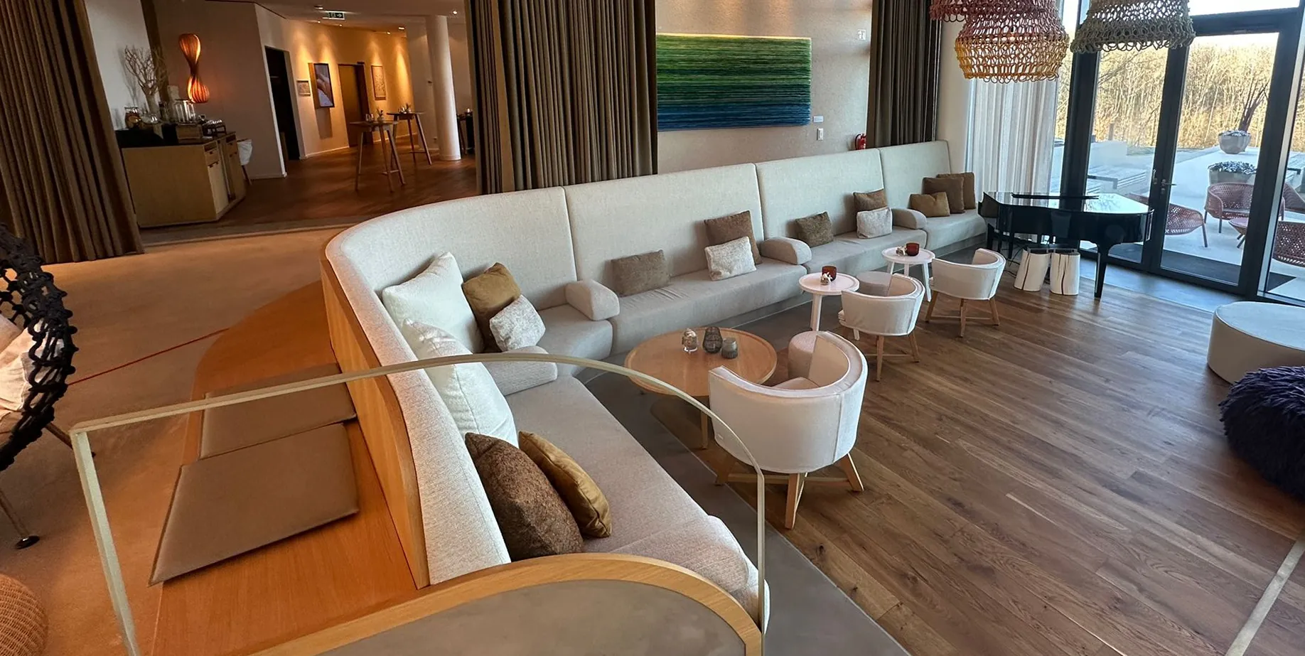 Lobby der Seezeitlodge mit langer Polsterbank, Sesseln, Vorhängen und Parkettboden