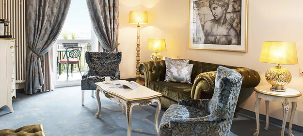 Hotelzimmer im Victors Hotel in Perl-Nennig mit gemusterten Sesseln und bodenlangen Vorhängen