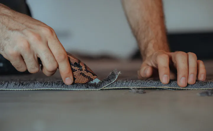 Teppichboden wird mit dem Cuttermesser passgenau zugeschnitten