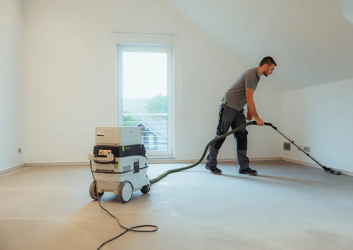 Handwerker reinigt den Untergrund vor dem Verlegen mit dem Industriesauger
