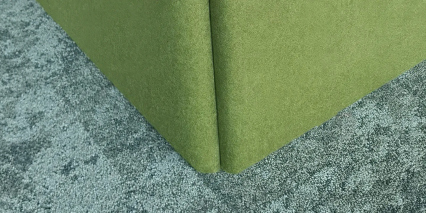Grüne Stoffbespannung an einer Kante über grauem Teppichboden